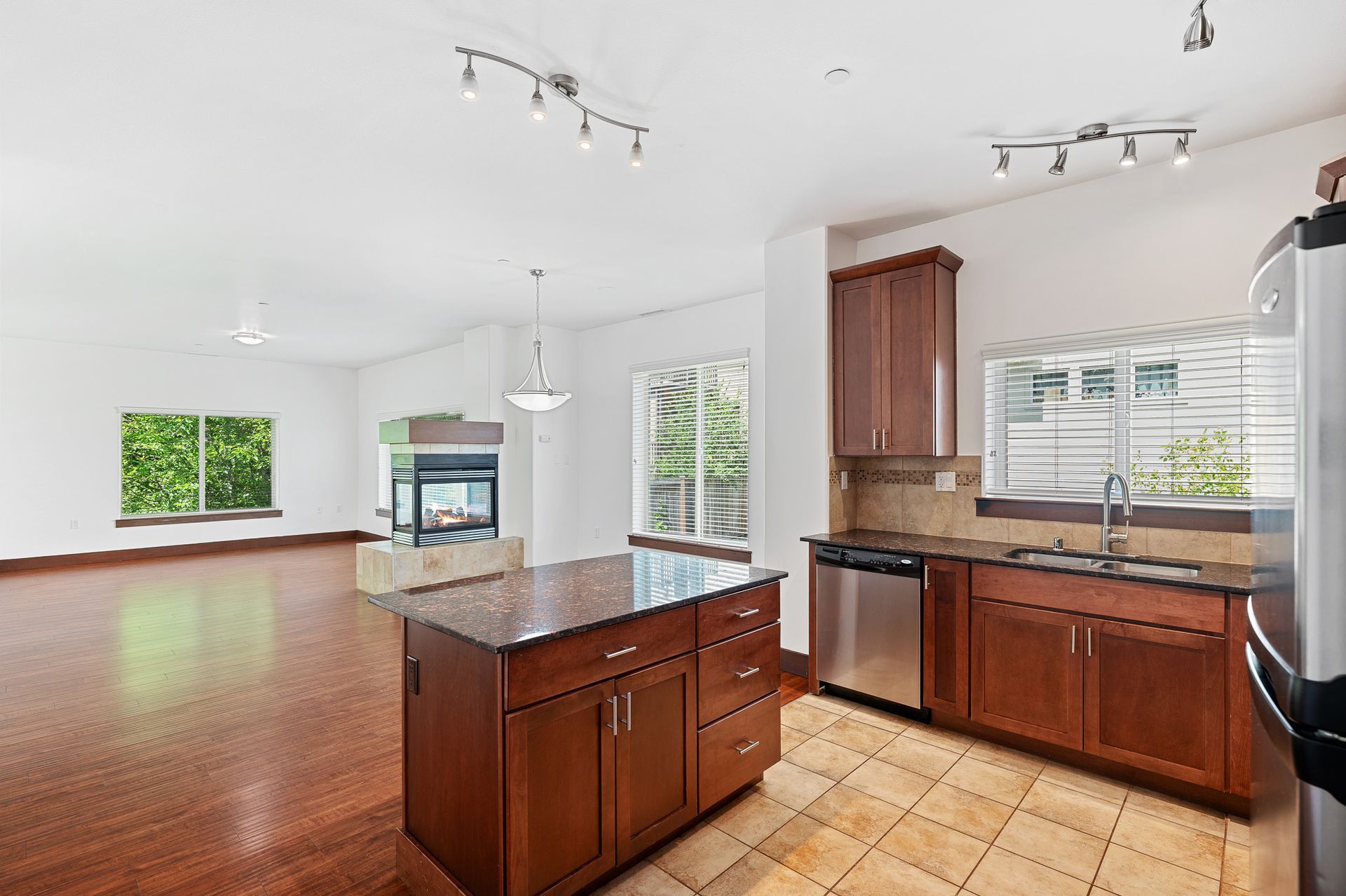 Photo of a kitchen, showing the living room in the background with plenty of natural lighting and a dining are as well