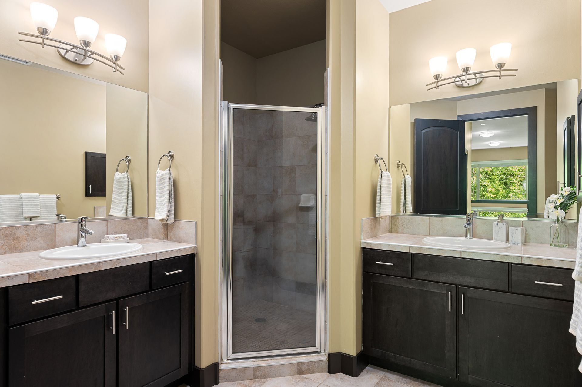 Photo of the bathroom showing two separate counters, sinks and vanity mirror areas, with the shower in between