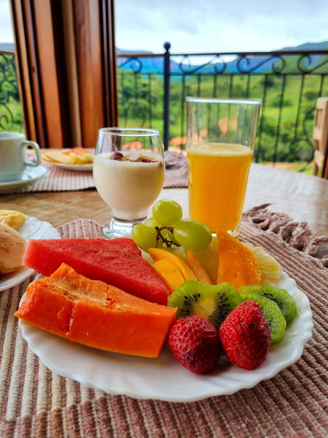 Um prato de frutas e um copo de suco de laranja sobre uma mesa.