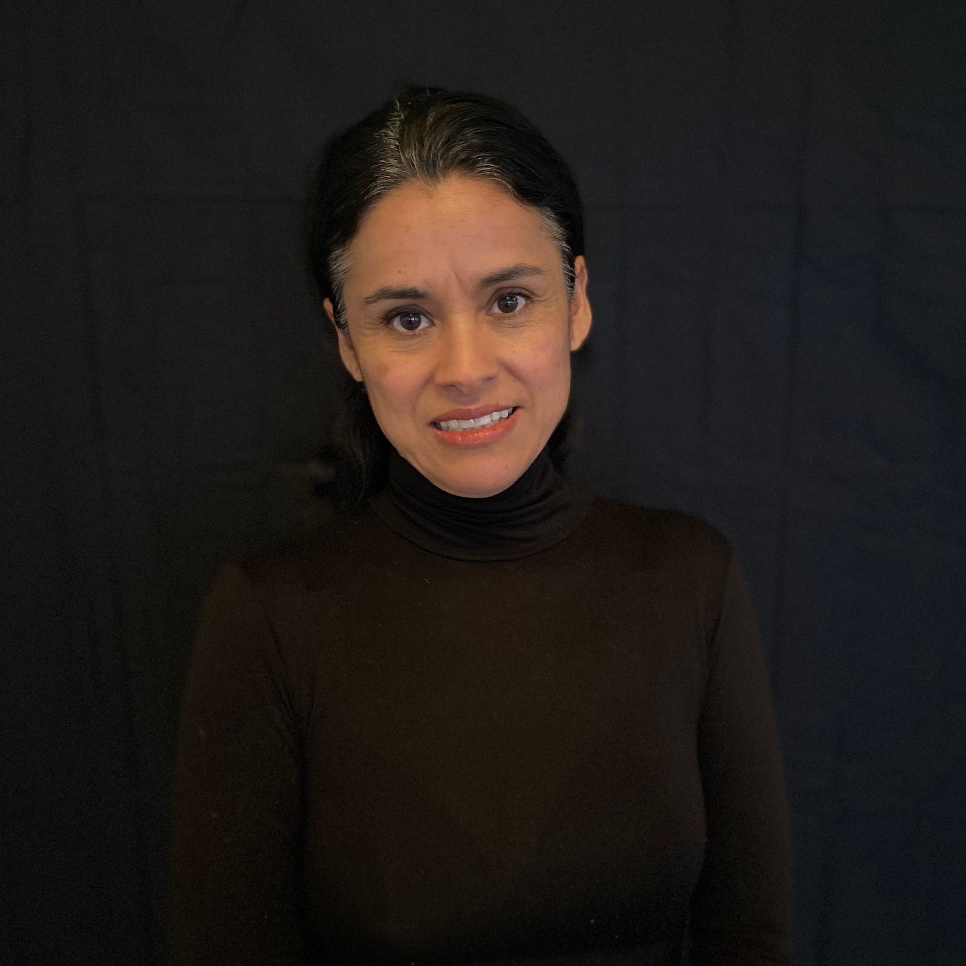 A woman wearing a brown turtleneck is smiling for the camera