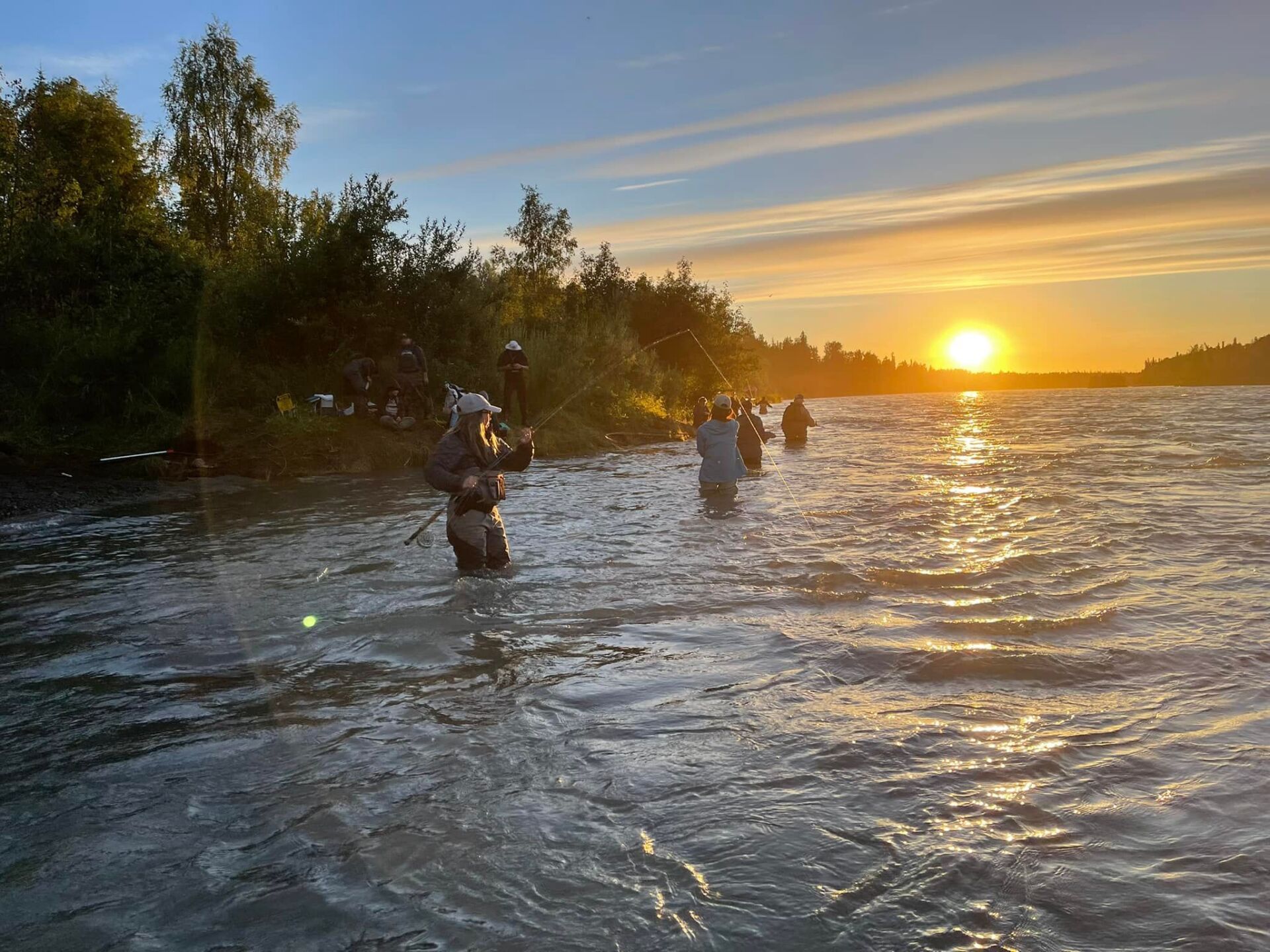 People wading and fishing in river
