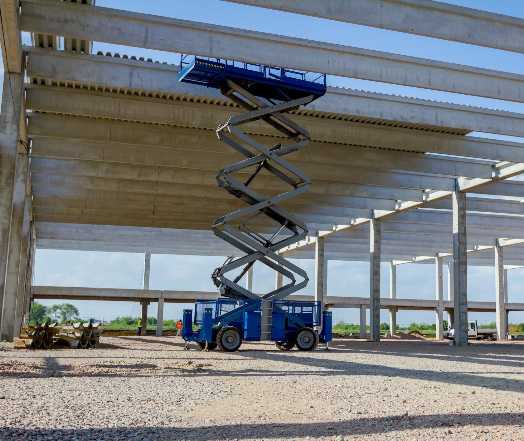 Un elevador de tijera azul se encuentra encima de un edificio en construcción.