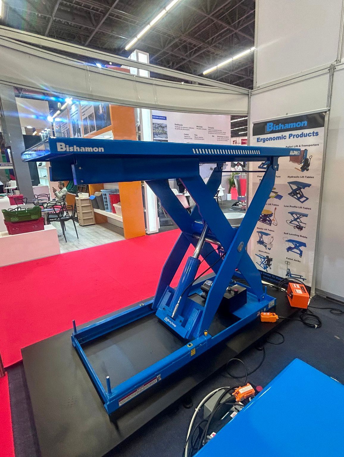 Un elevador de tijera azul está sentado sobre una alfombra roja en una habitación.