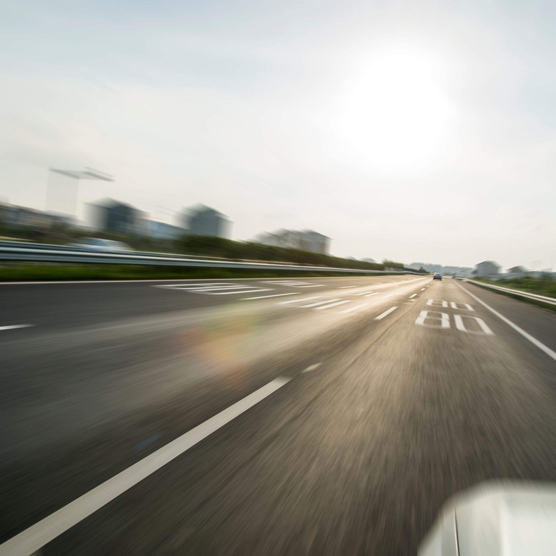 A blurry picture of a highway with a white car driving down it.