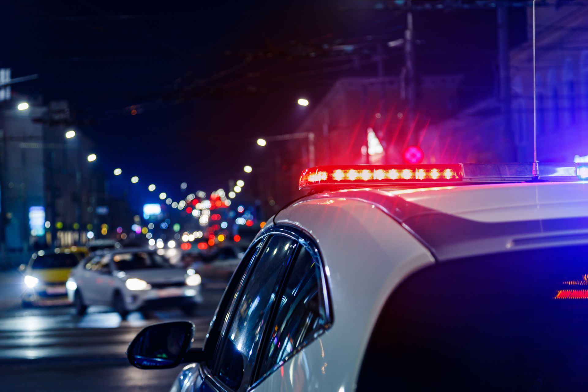 A police car is parked on the side of the road at night.