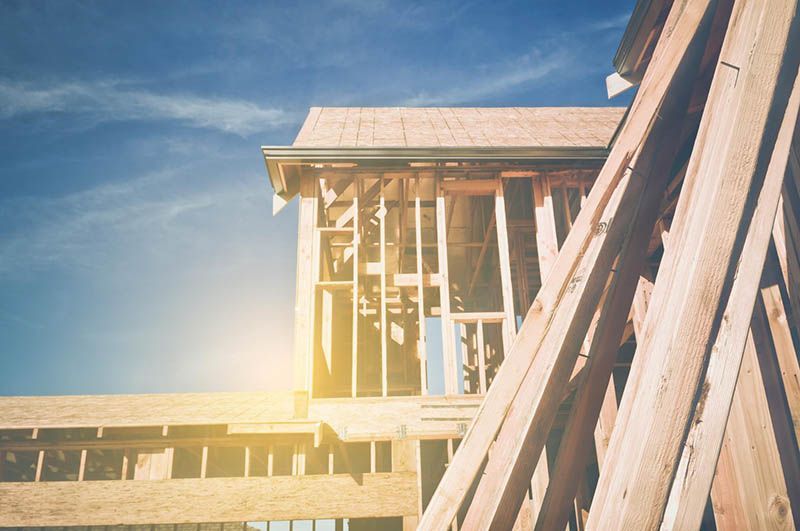 Ossature en bois d'un bâtiment en construction sous un ciel lumineux.
