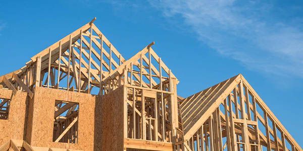Ossature en bois d'une maison en construction contre un ciel bleu.