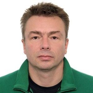 A man is wearing a green jacket and a black shirt.