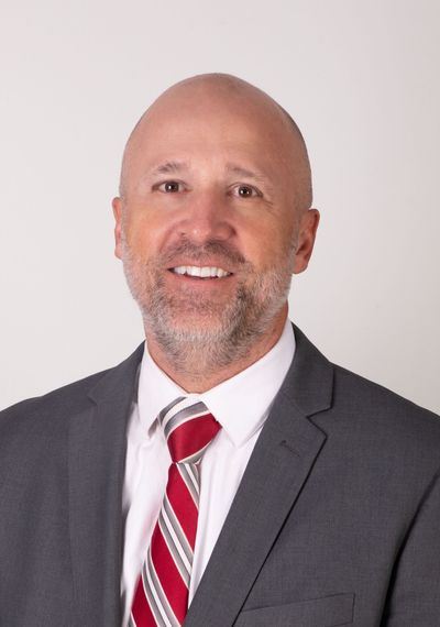 A man in a suit and tie is standing in front of a brick wall.