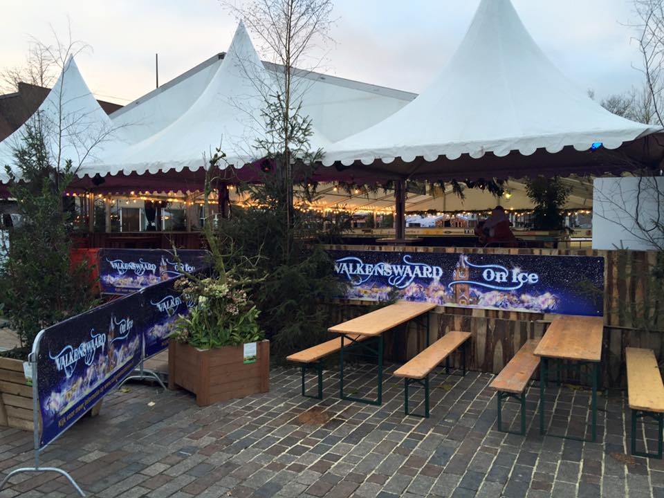 Een tent met tafels en banken ervoor