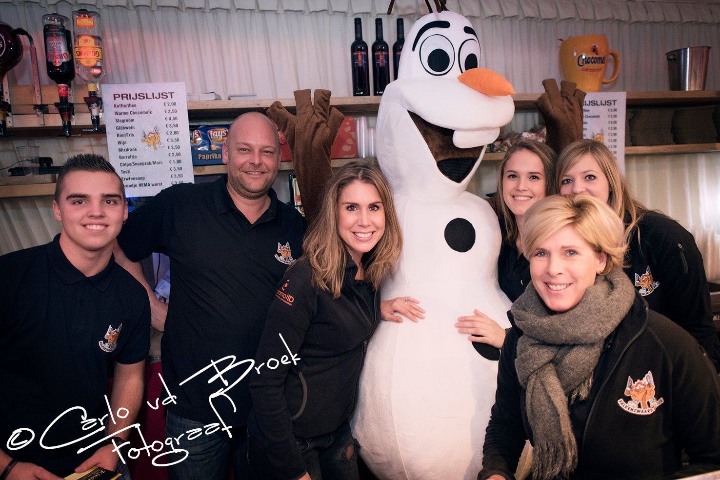 Een groep mensen poseren voor een foto met een opgezette sneeuwpop
