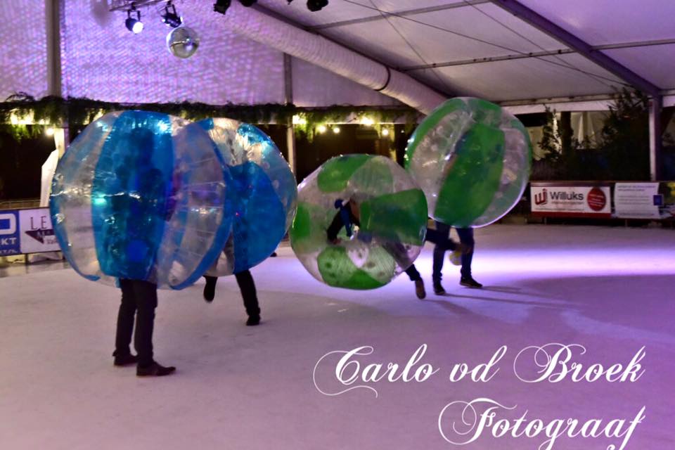 Een groep mensen speelt bubbelvoetbal op een ijsbaan.