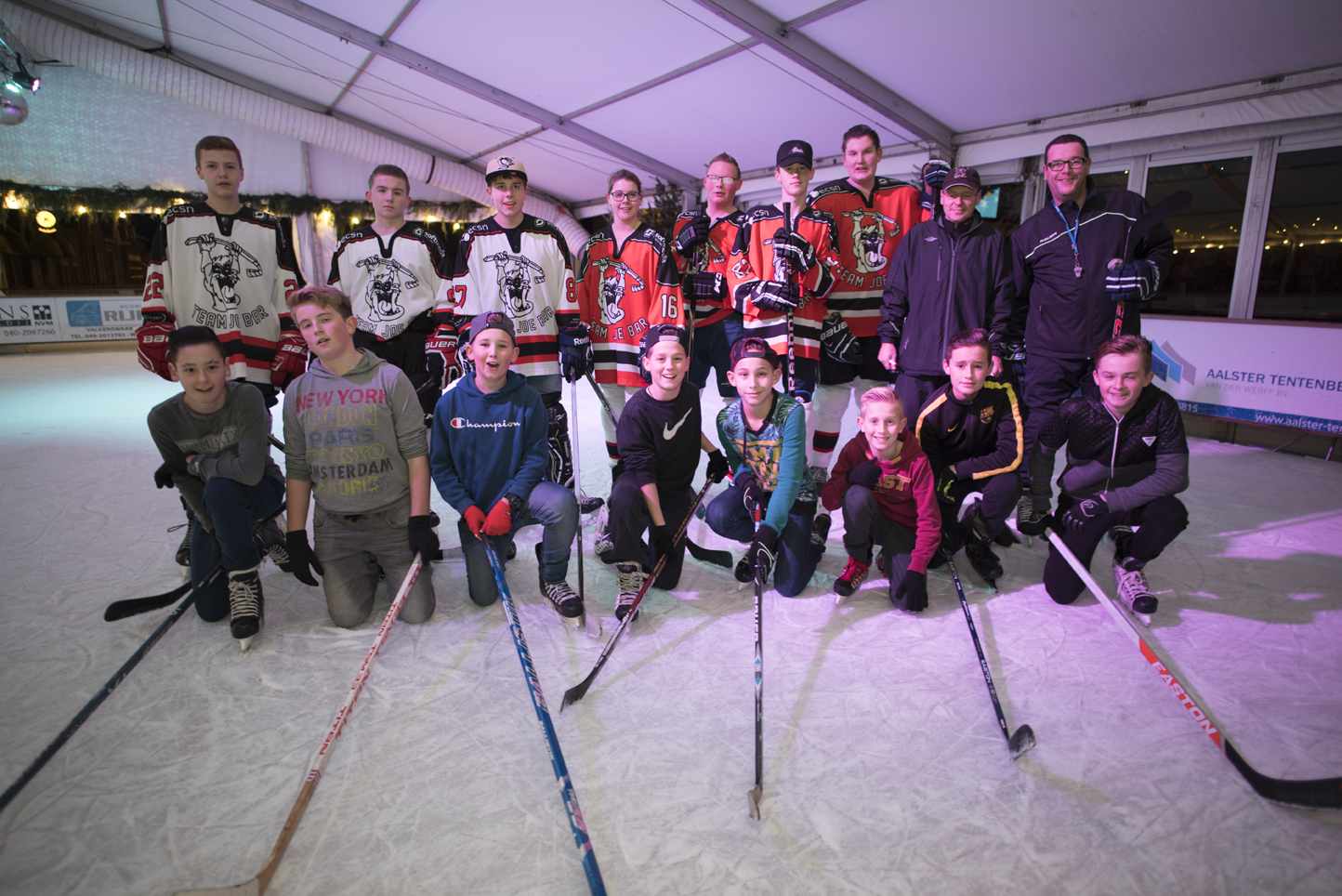 Een groep hockeyspelers poseert voor een foto op een ijsbaan.