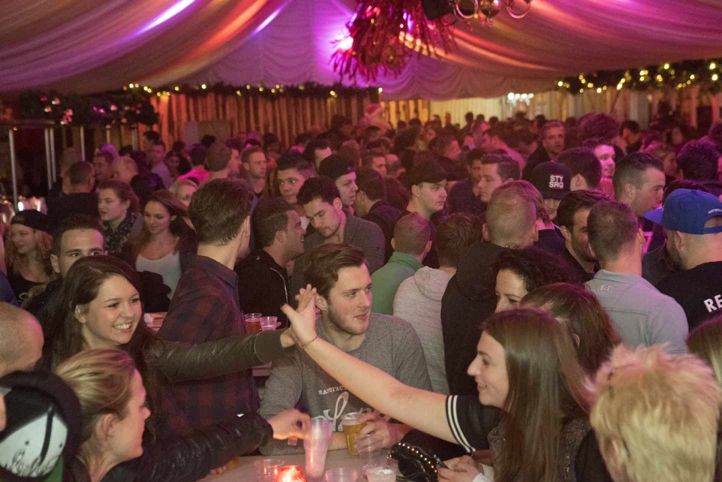 Een menigte mensen is verzameld in een kamer met paarse lichten.