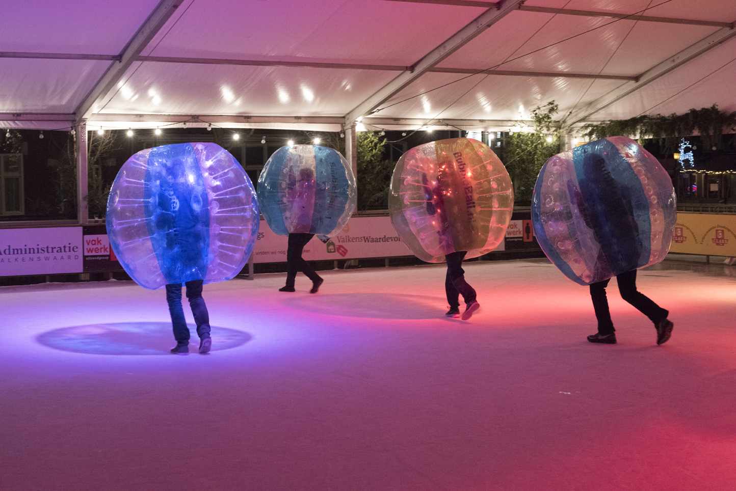 Een groep mensen speelt bubbelvoetbal op een ijsbaan.