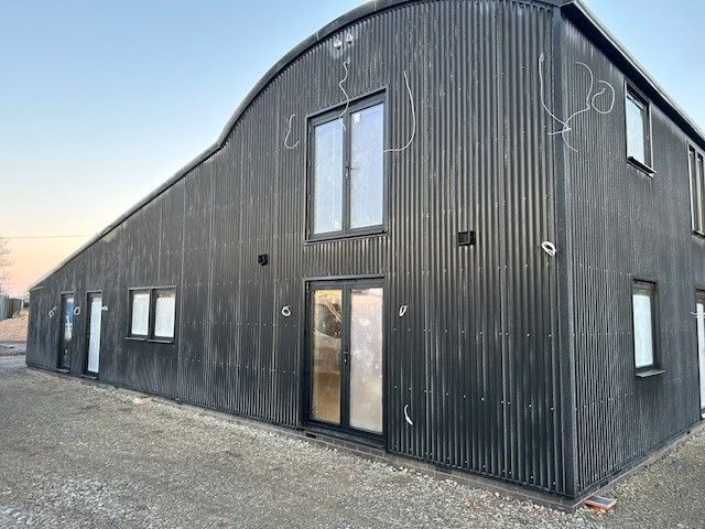 This newly built live-work unit combines modern design with functional living space. The striking feature of the building is its curved roof, which creates a dynamic and sleek silhouette against the sky, providing both aesthetic appeal and practical benefits such as improved water drainage. 