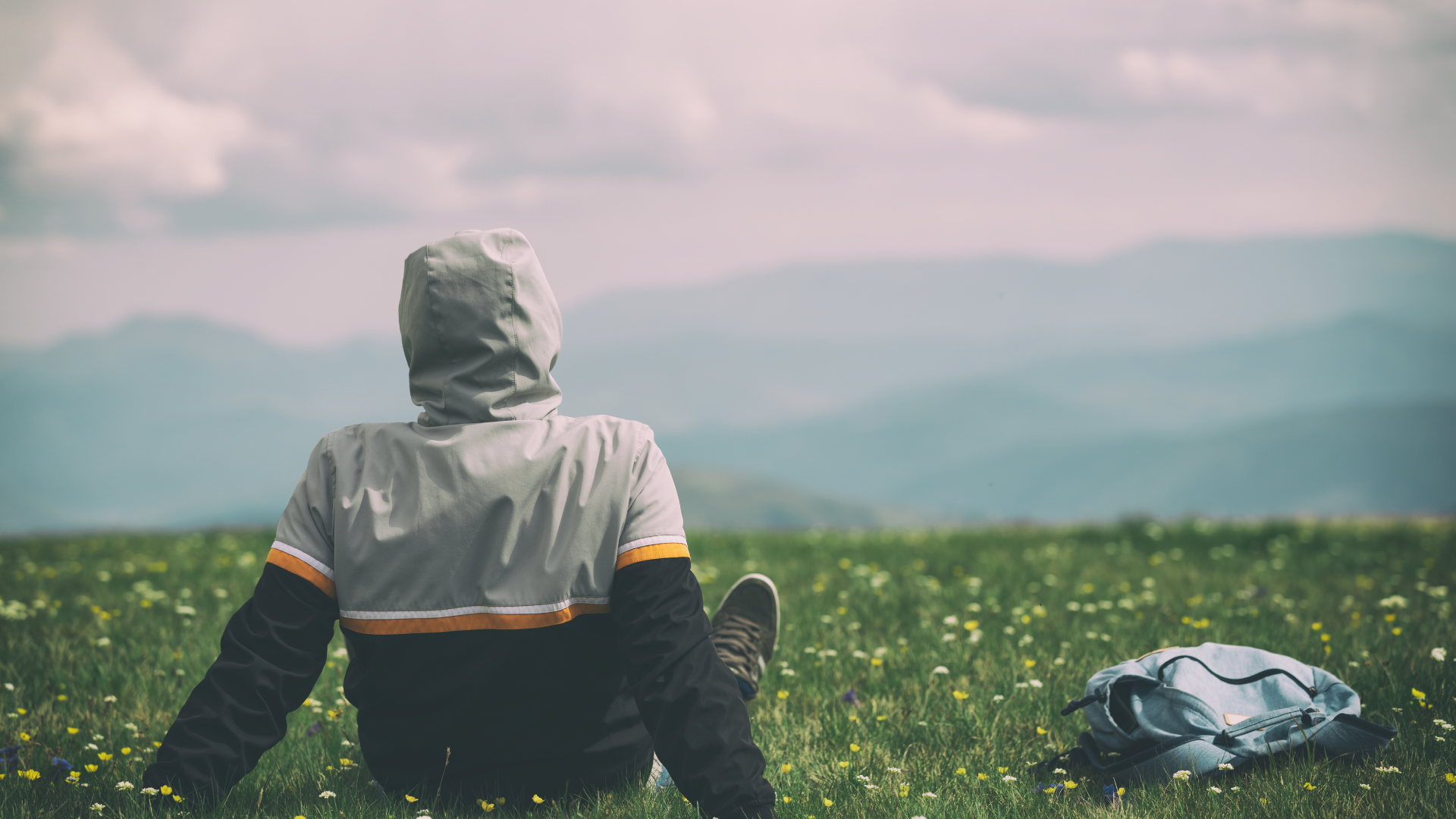 Woman in yellow shirt with eyes closed, sunlight filtering through tall grass.
