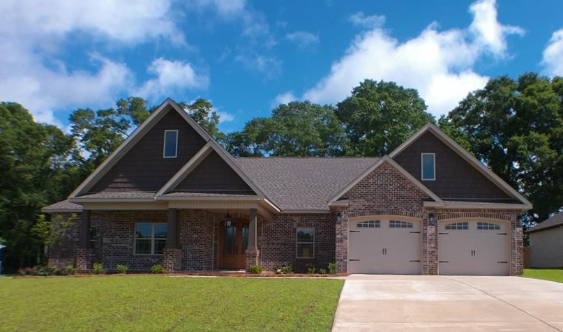 Brick house with brown roof, two-car garage, and green lawn under a blue sky.