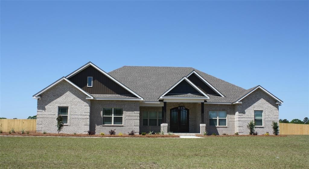 Ranch-style house with gray brick exterior, gray roof, black trim, and double front doors against a clear blue sky.
