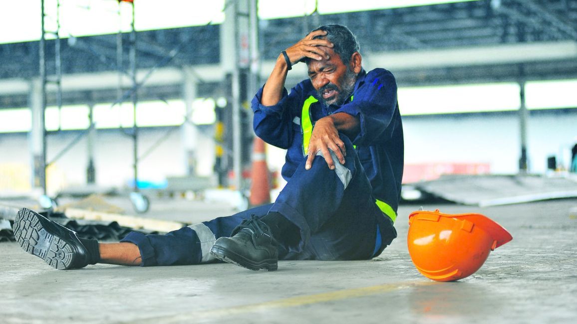 a man is sitting on the floor next to a hard hat .