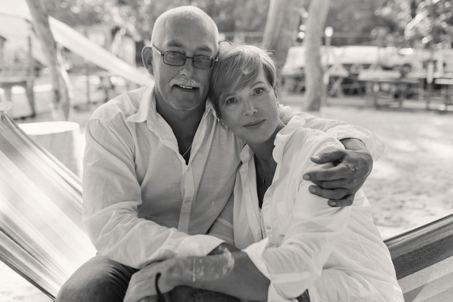 A black and white photo of a man and woman sitting in a hammock.