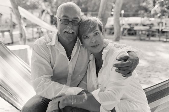 A black and white photo of a man and woman sitting in a hammock.