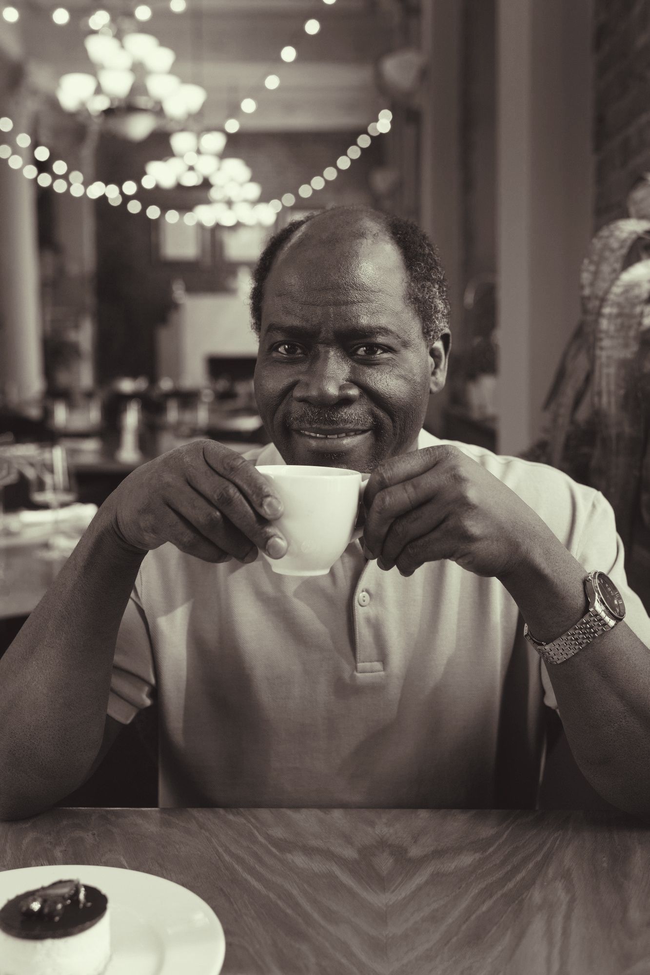 A man is sitting at a table drinking a cup of coffee