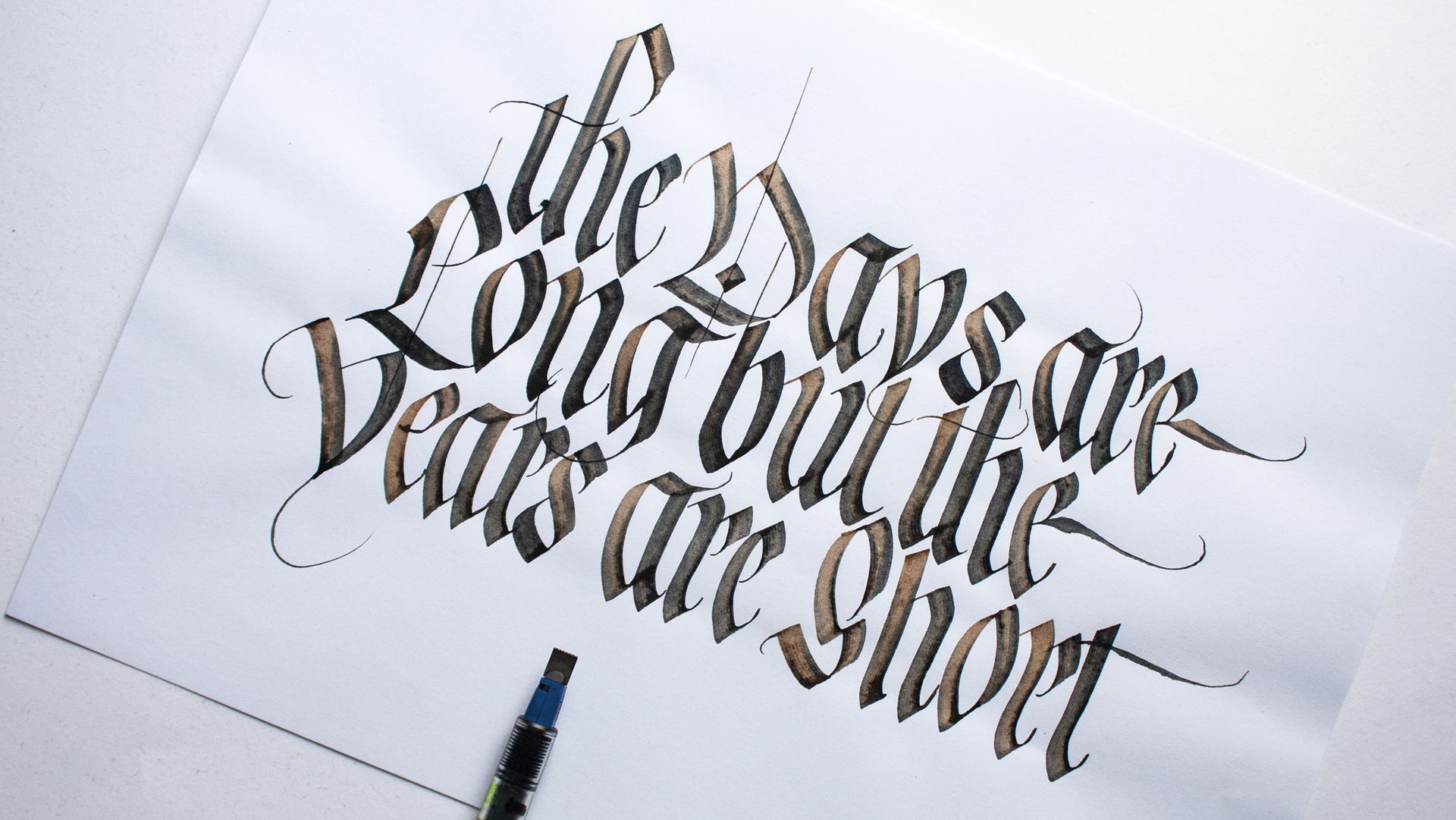 Blackletter calligraphy design with the message 'The days are long but the years are short'.