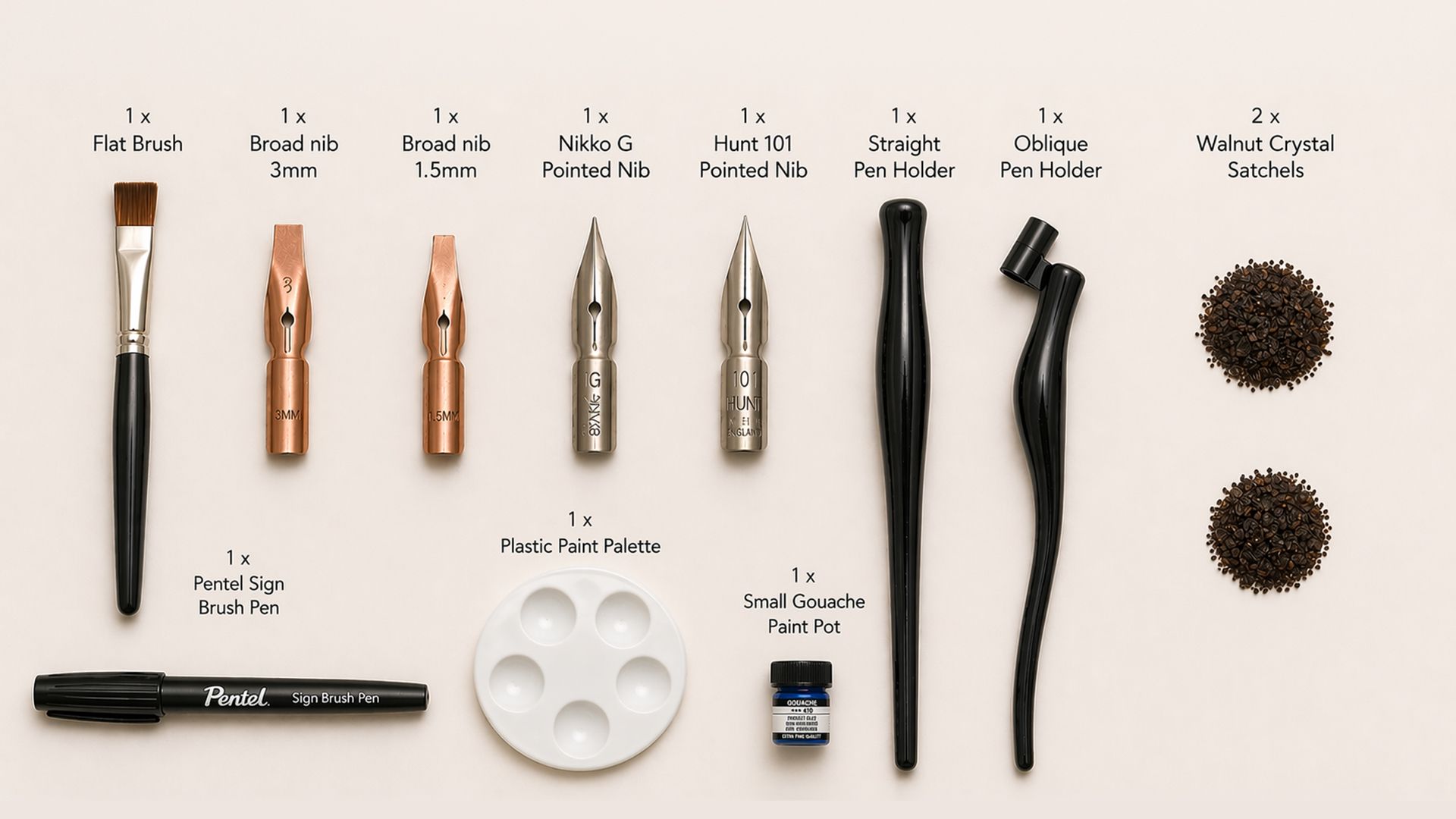 Calligraphy kit laid out with pens, nibs, ink, palette, and paper examples on a white background