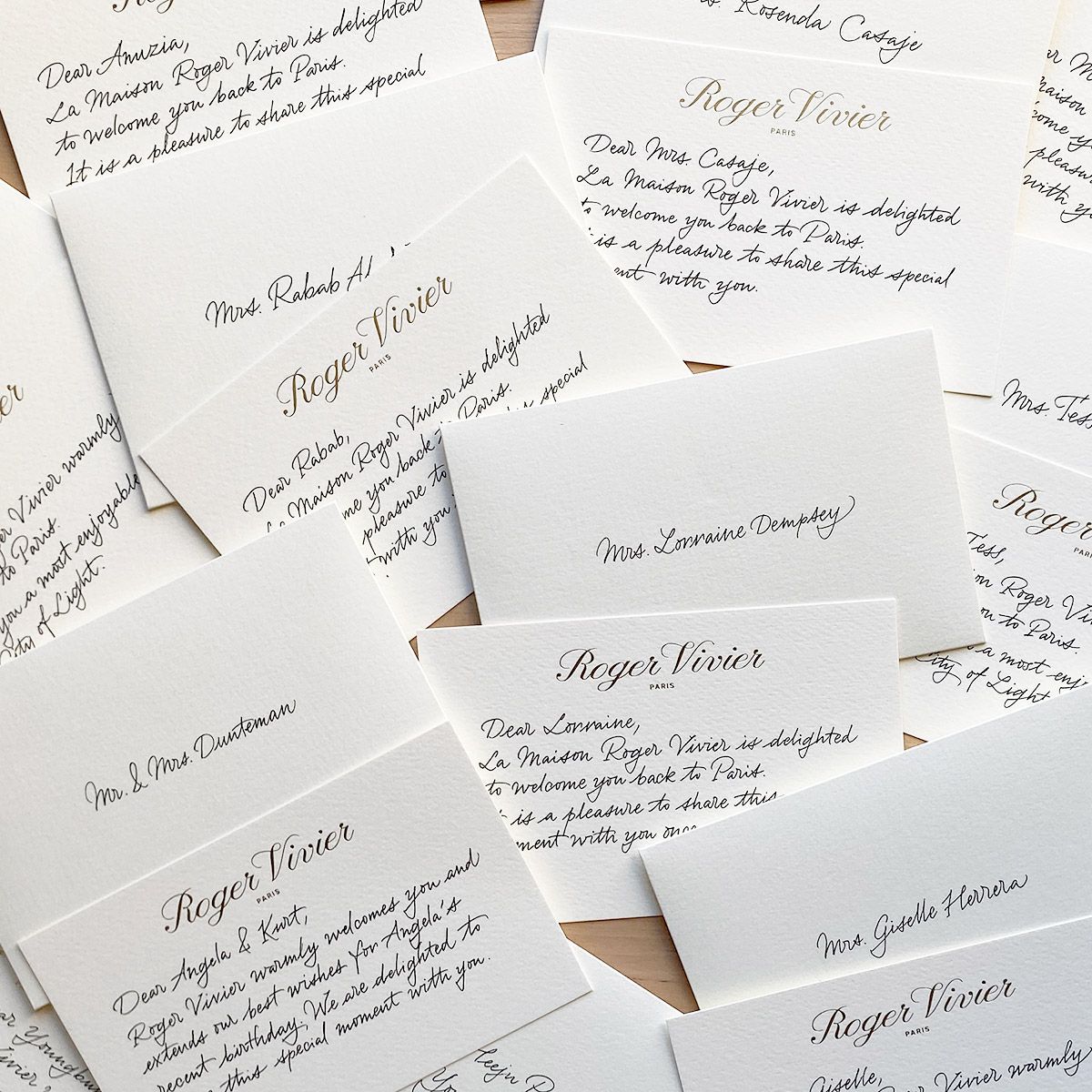 Scattered handwritten invitation cards with elegant cursive text on a white background