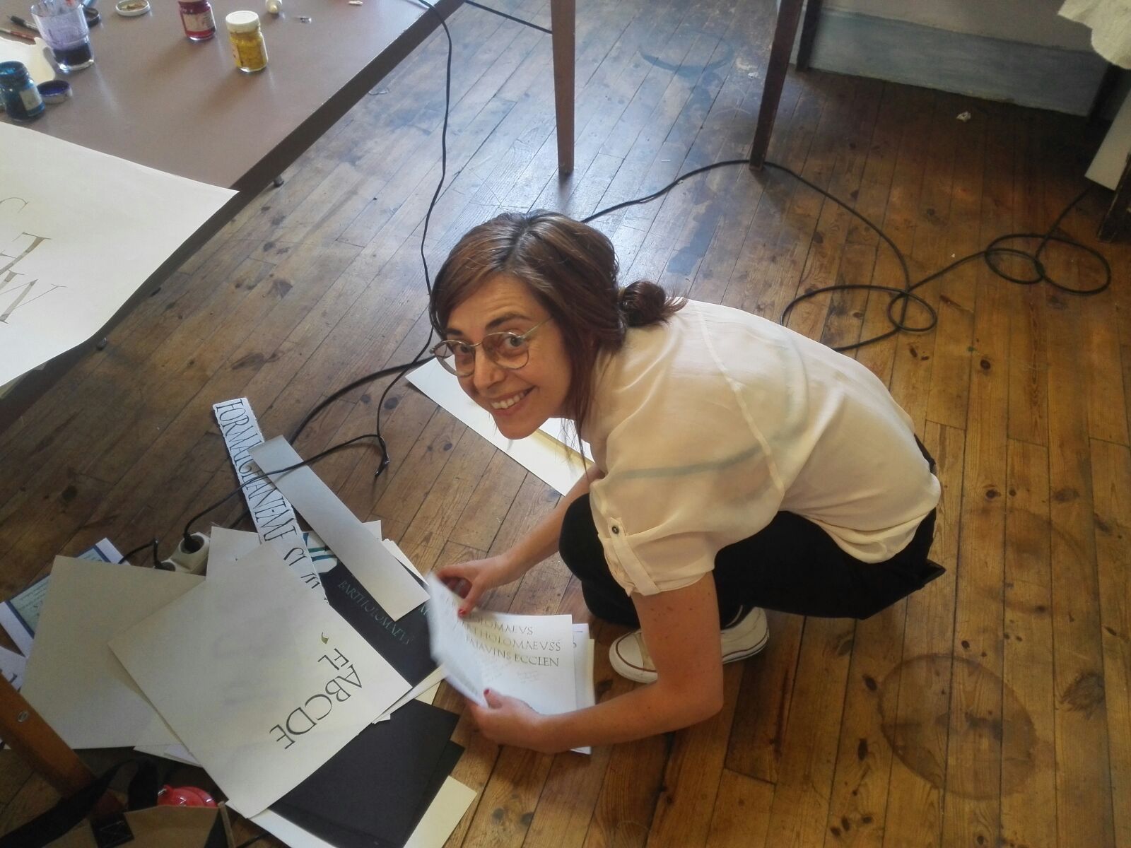 Maria Montes portrait looking at the camera smiling while filing some calligraphy writing practice.