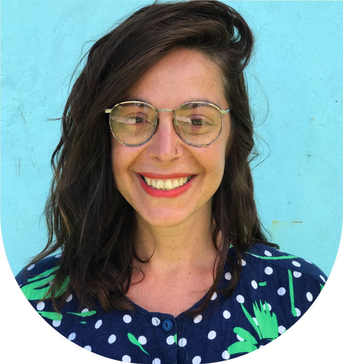 Maria Montes full colour portrait over a blue background, smiling and wearing a red lipstick.