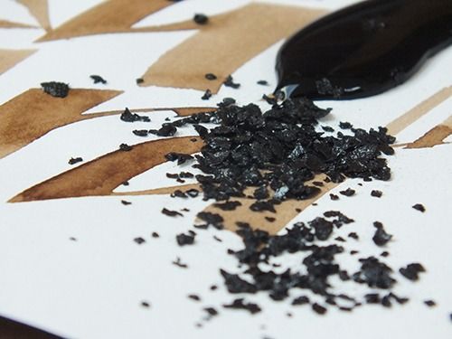 A close-up image of walnut crystals on top of white textured paper from the website www.kalligrafie.com