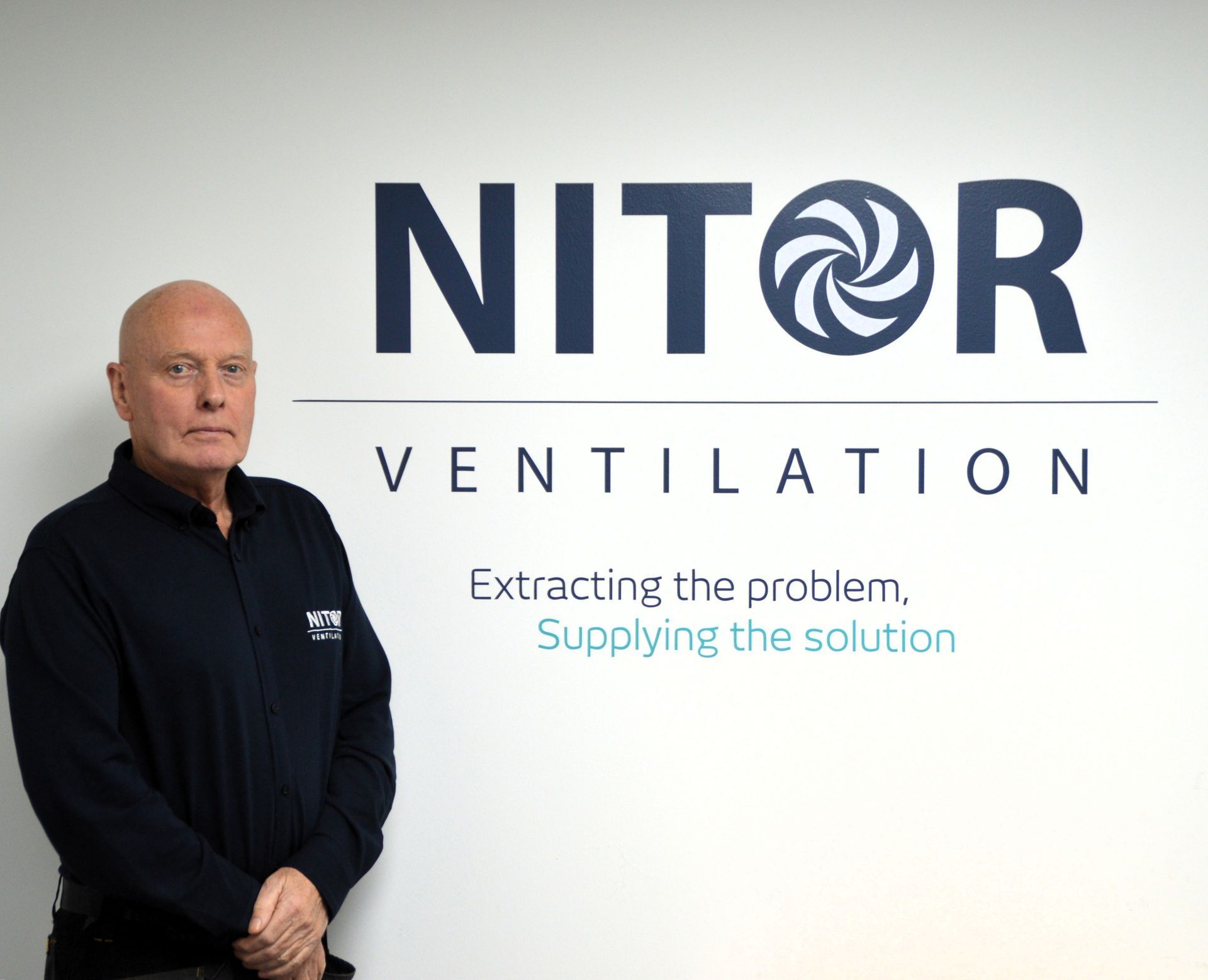 Man standing in front of a white wall with 