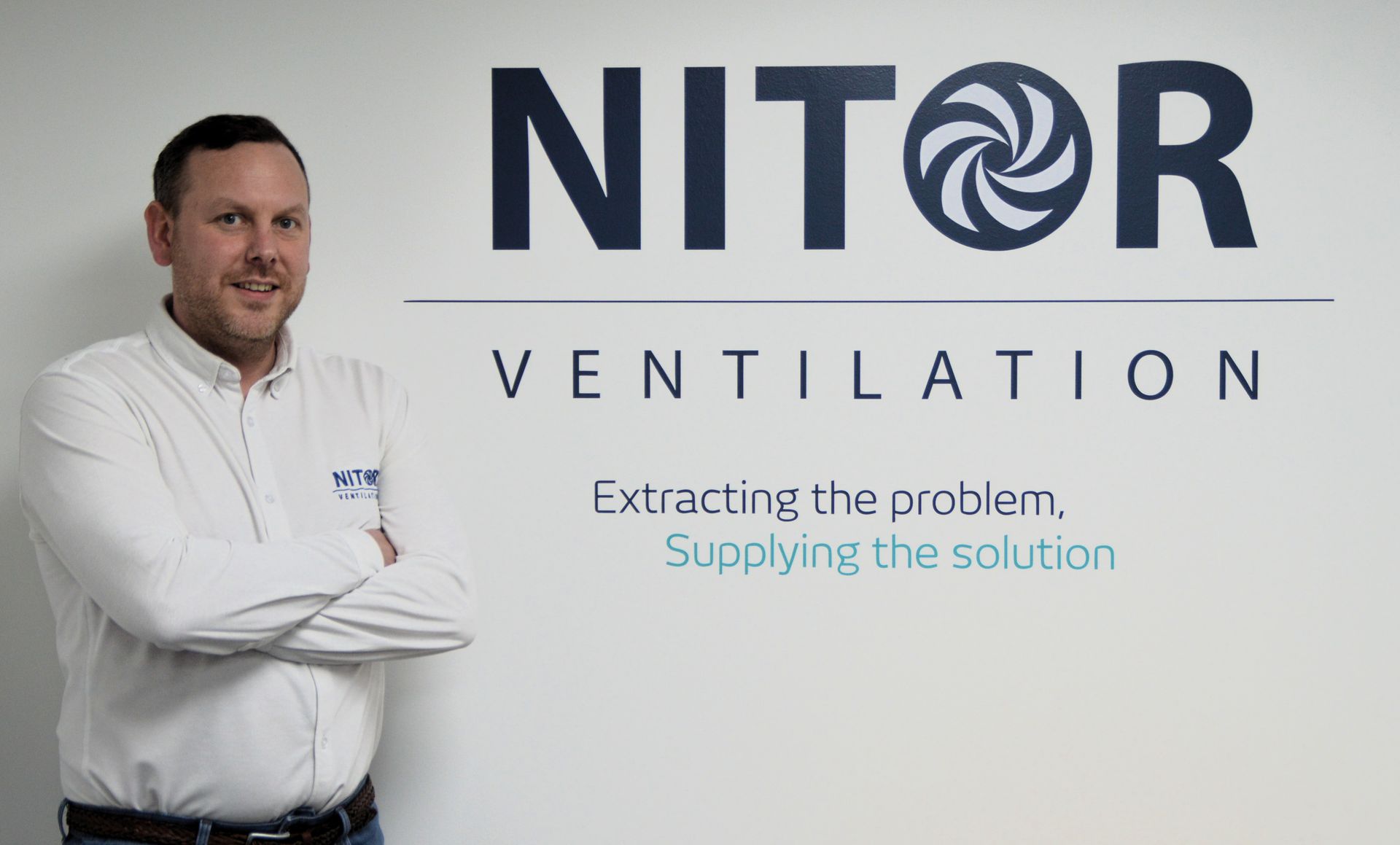 Man in white shirt stands with arms crossed in front of a Nitor Ventilation logo.