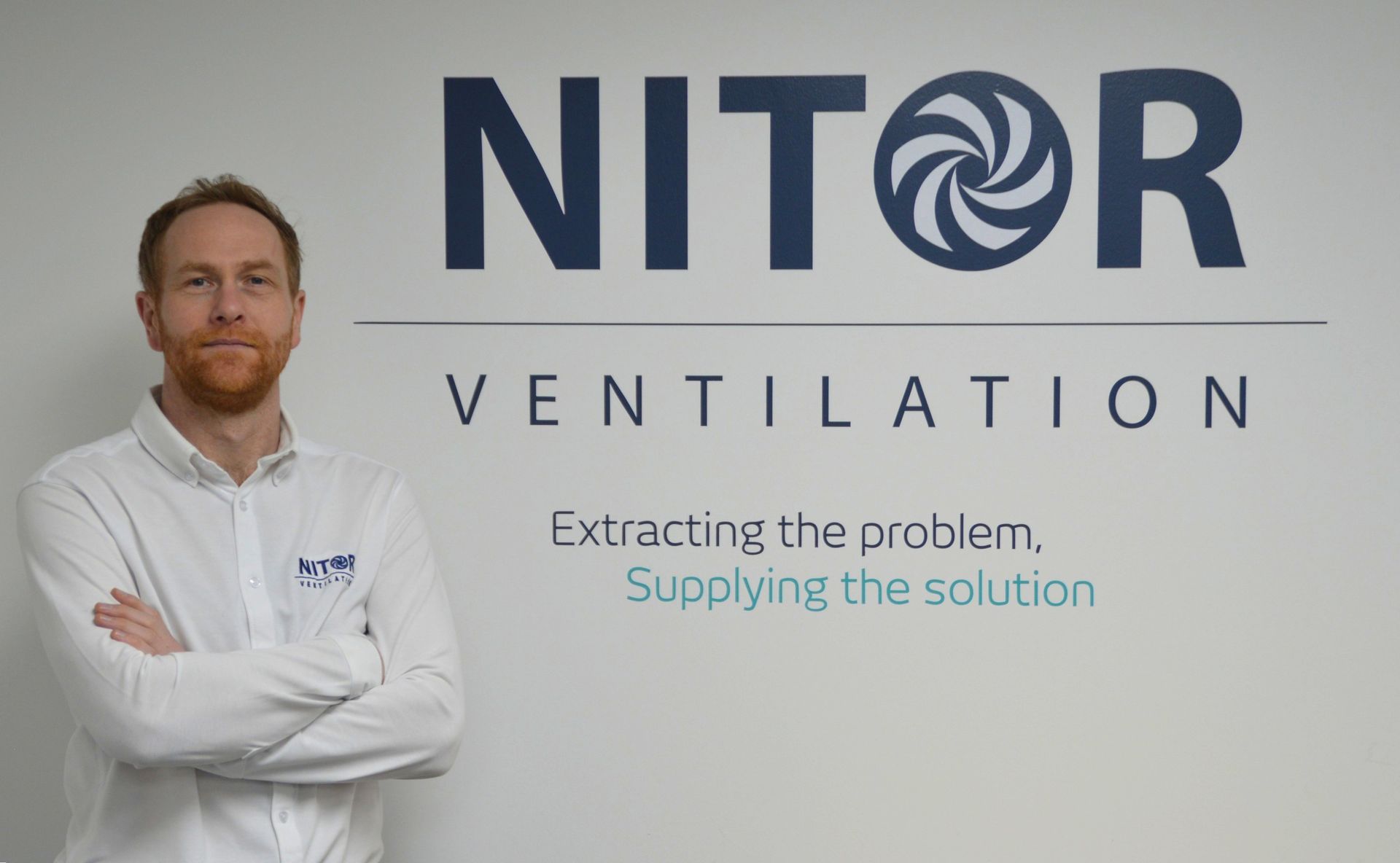 Man standing in front of a wall with a company logo 