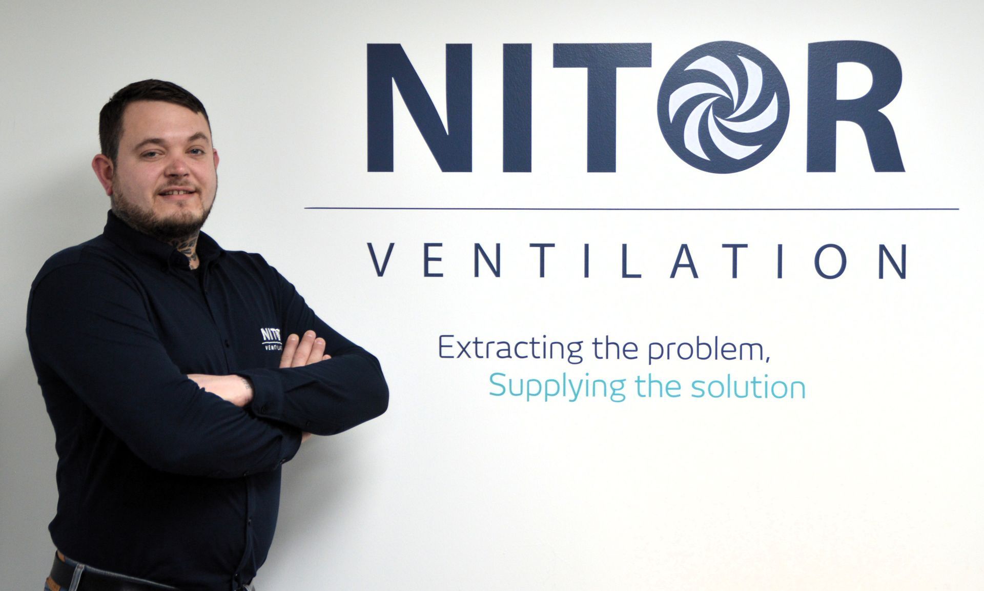 Man with arms crossed standing next to a 