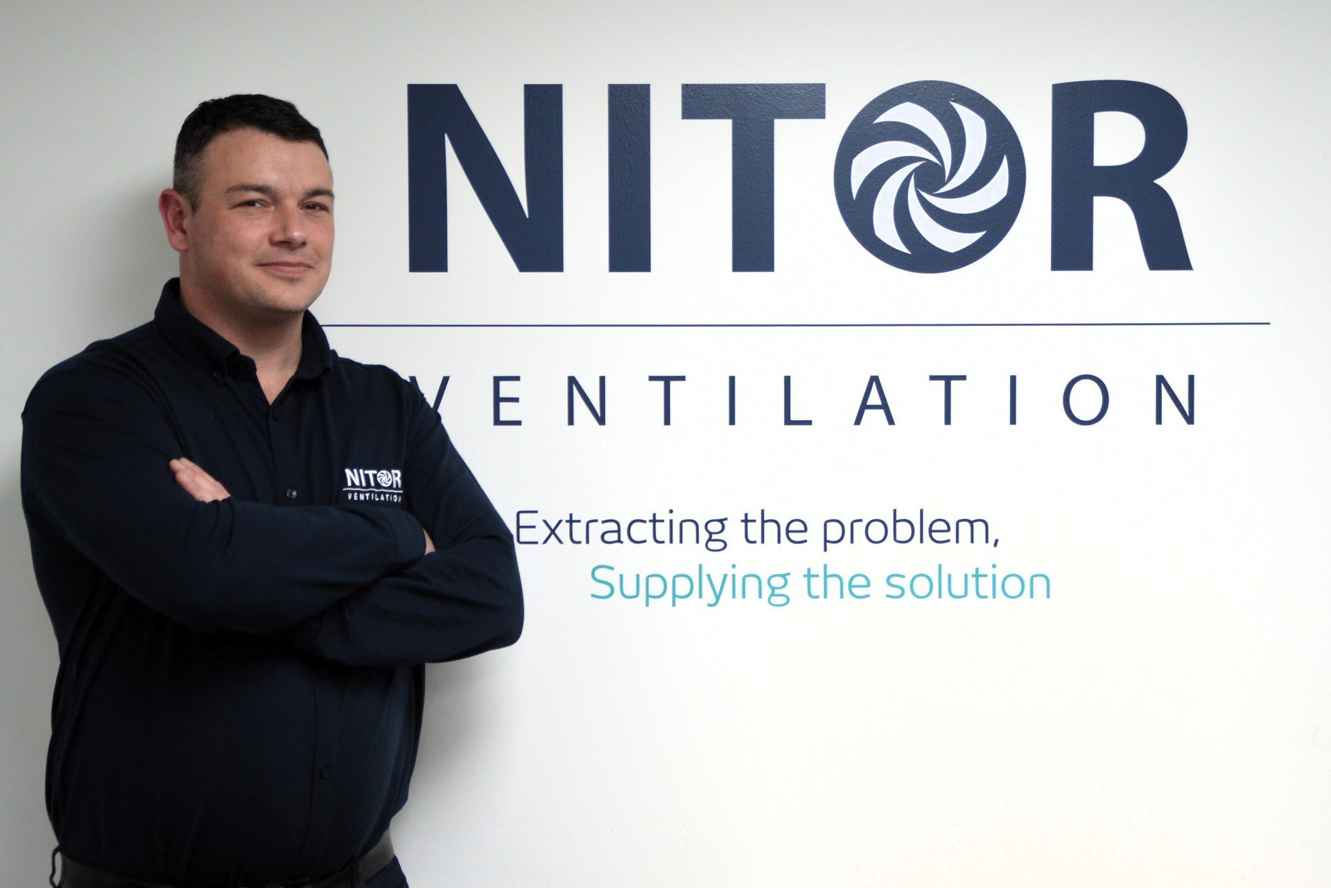 Man with arms crossed standing next to 