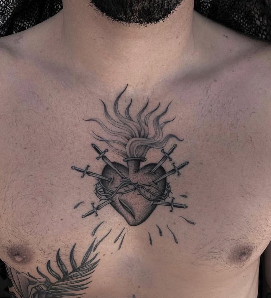 Black and gray Sacred Heart tattoo on chest with swords and flames.