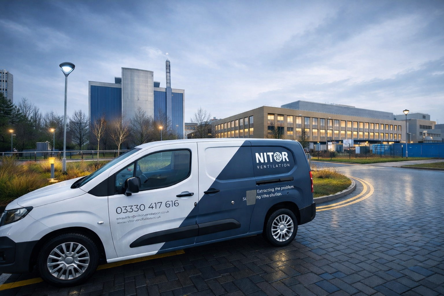 White and blue Nitor van parked on a circular driveway in front of a modern building with a cloudy sky.