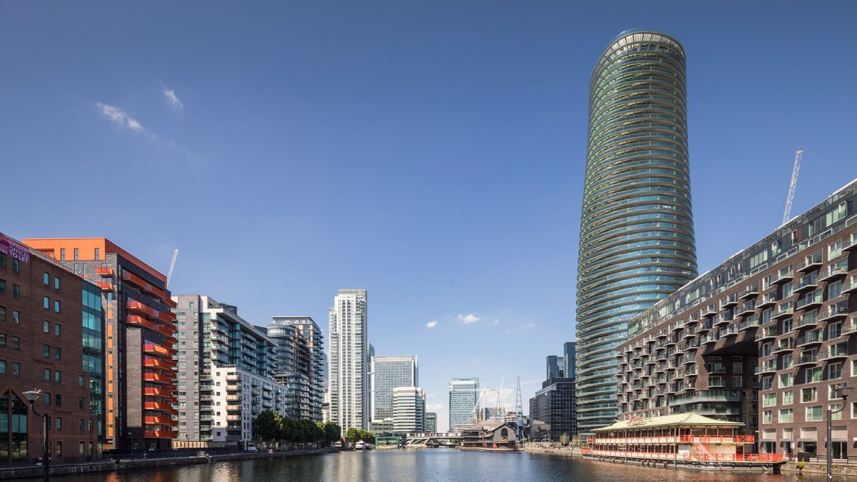 Cityscape with tall modern buildings along a waterway under a clear blue sky.