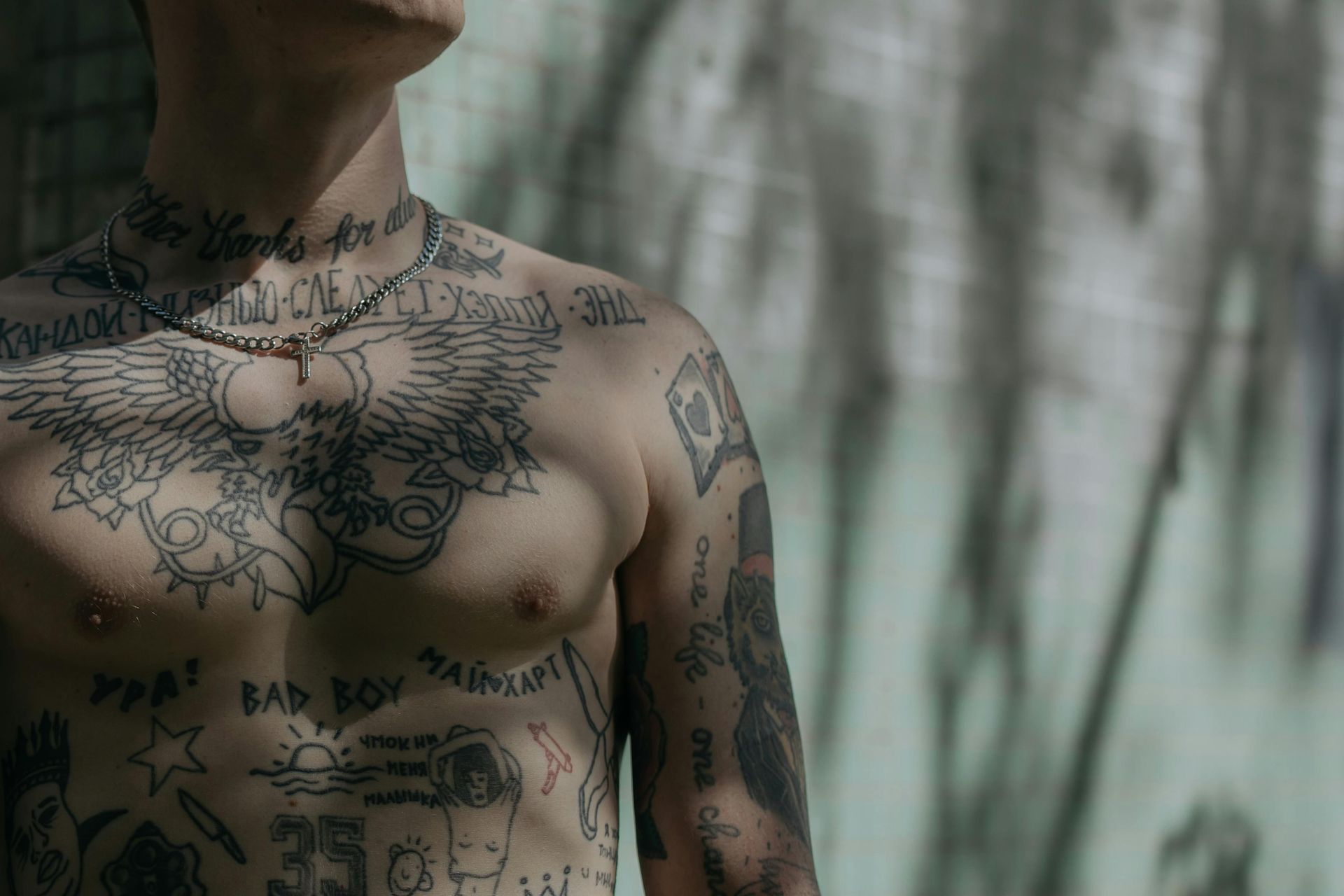 Man with torso tattoos, standing outdoors.