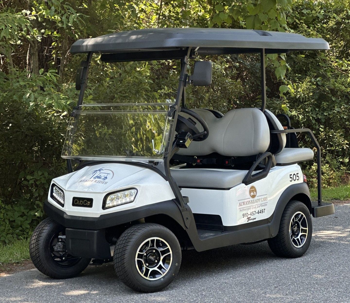 A white golf cart is parked on the side of the road.