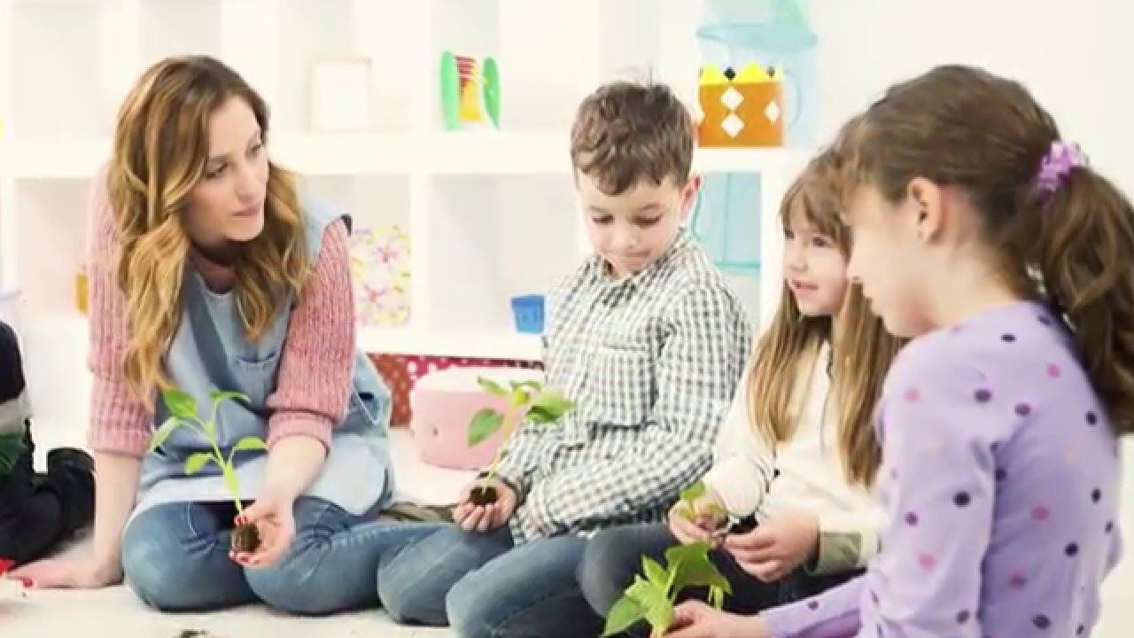 A group of children are sitting on the floor with a teacher.