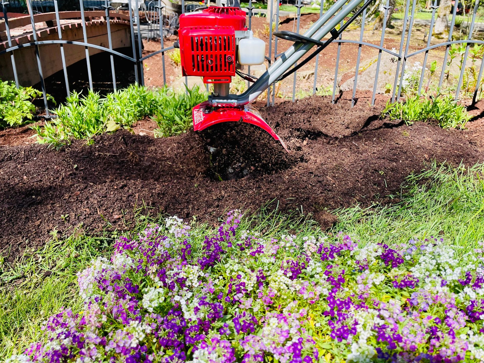 A red lawn mower is sitting in the middle of a flower bed.