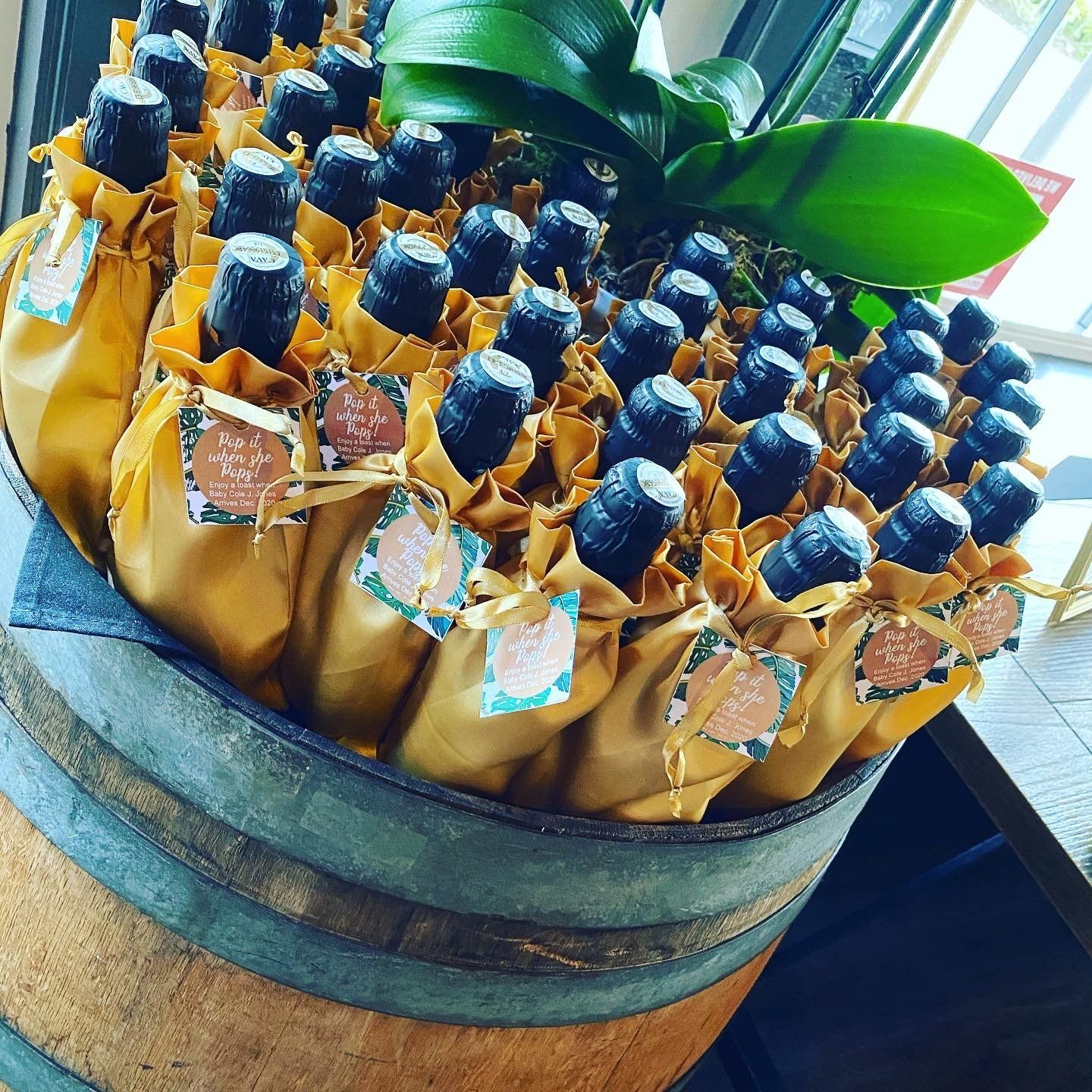 A bunch of bottles wrapped in yellow paper on top of a wooden barrel