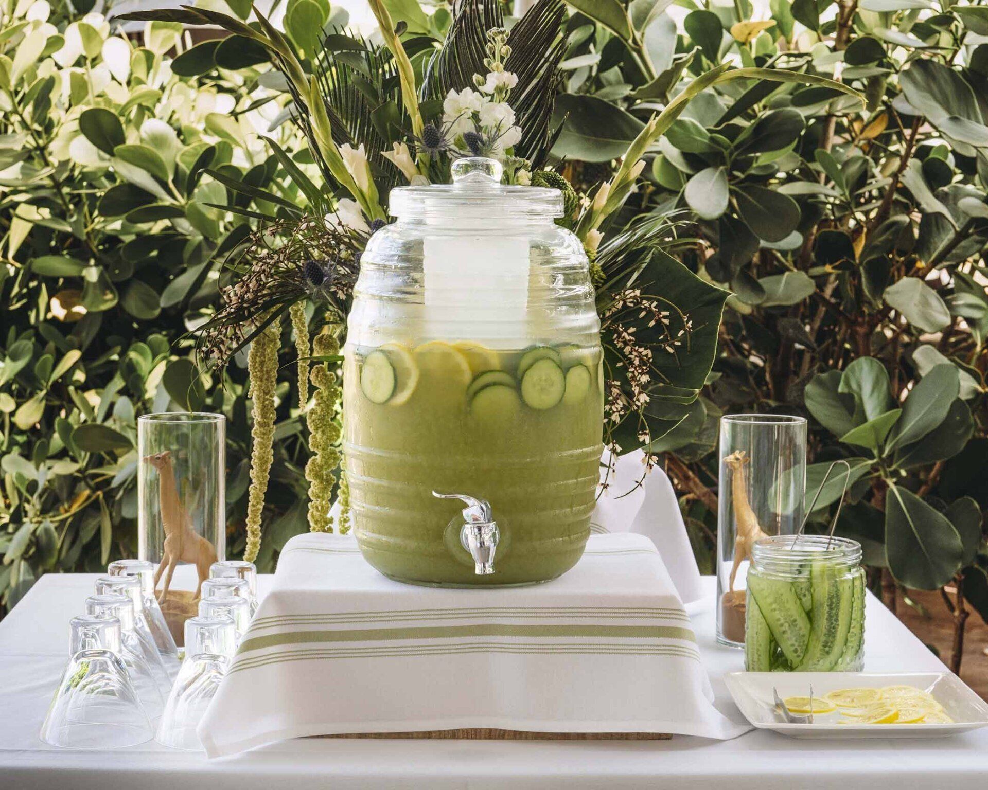 A table with a drink dispenser and glasses on it