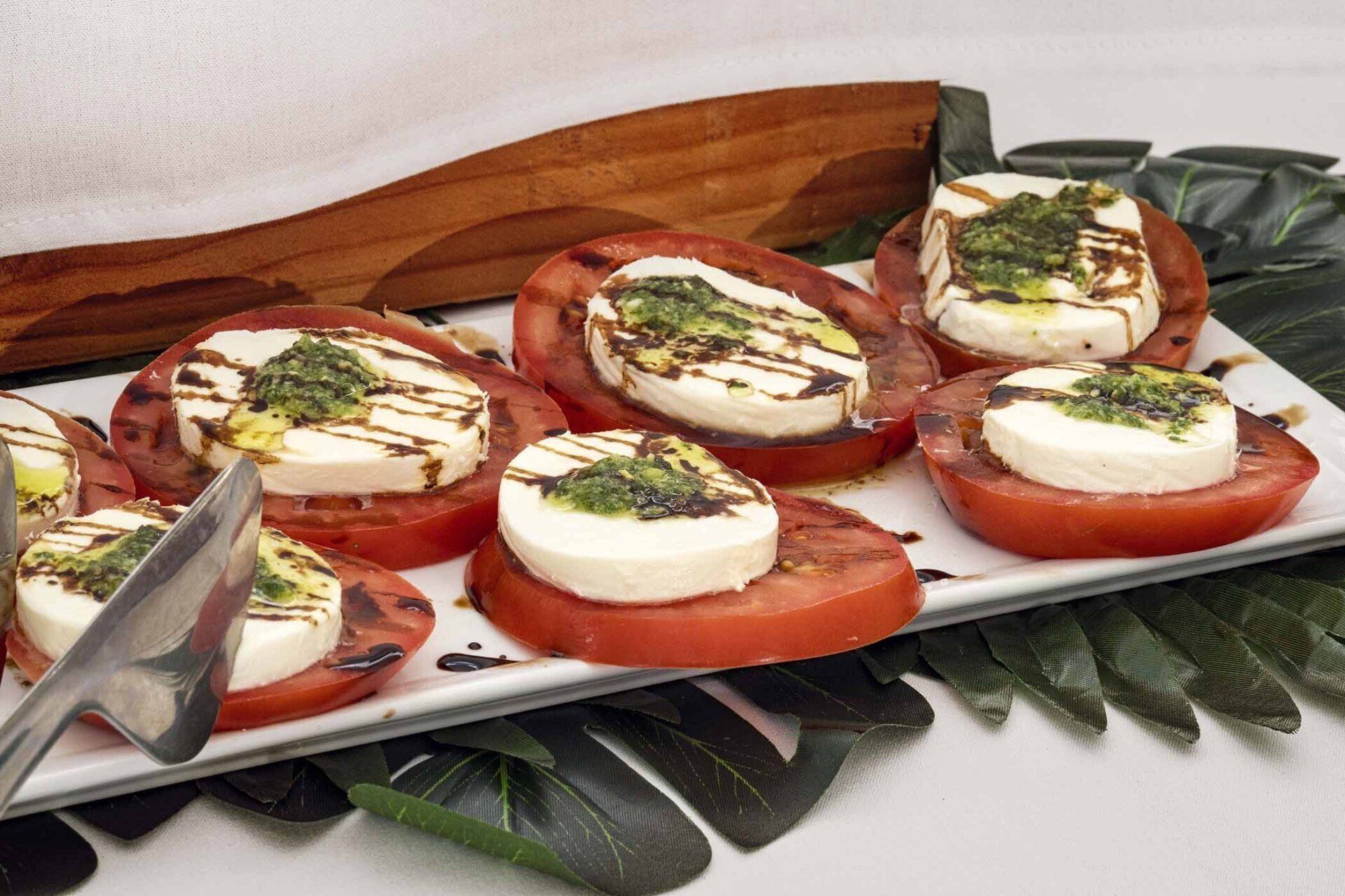 A white plate topped with sliced tomatoes and mozzarella cheese