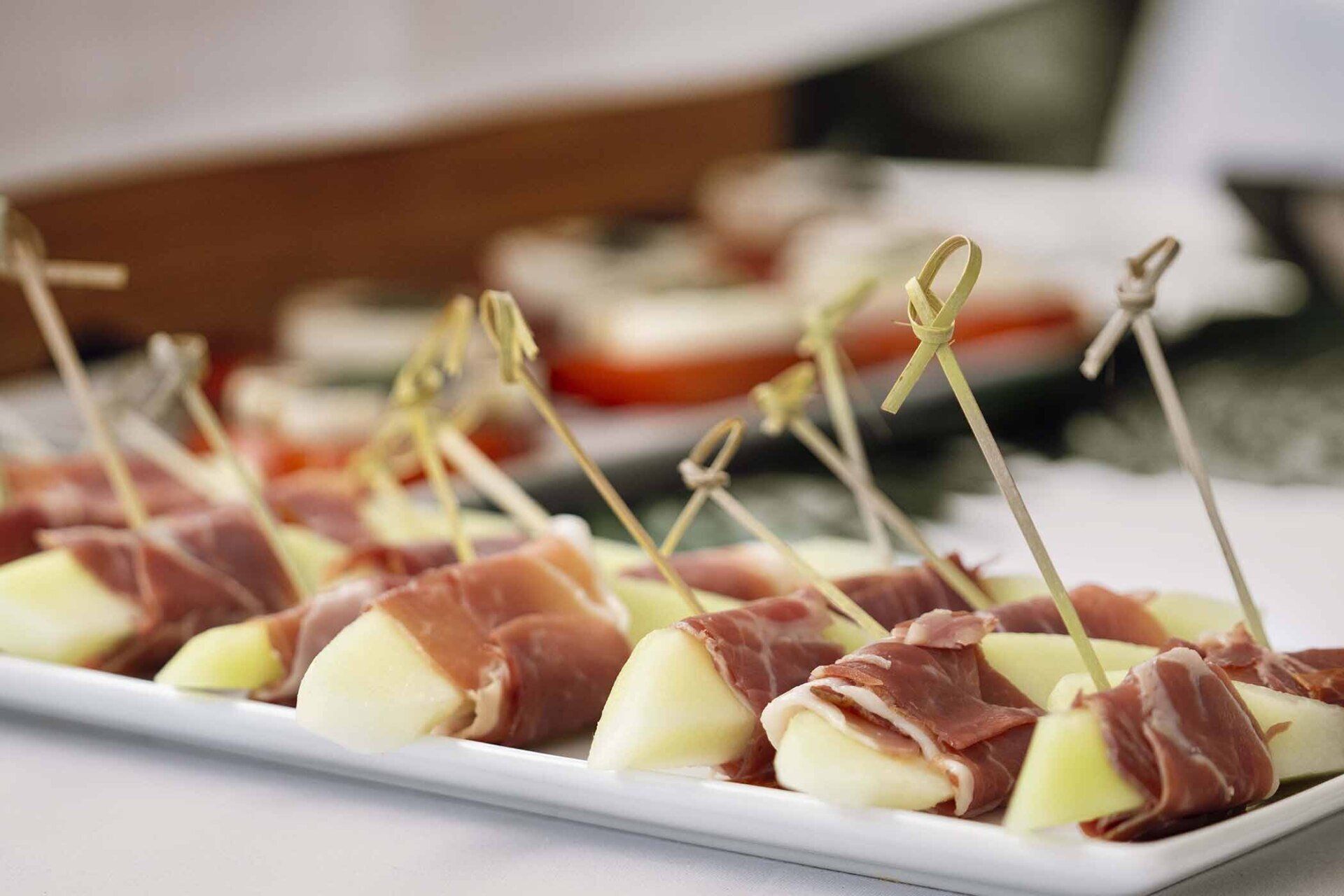 A white plate topped with meat and melon on toothpicks