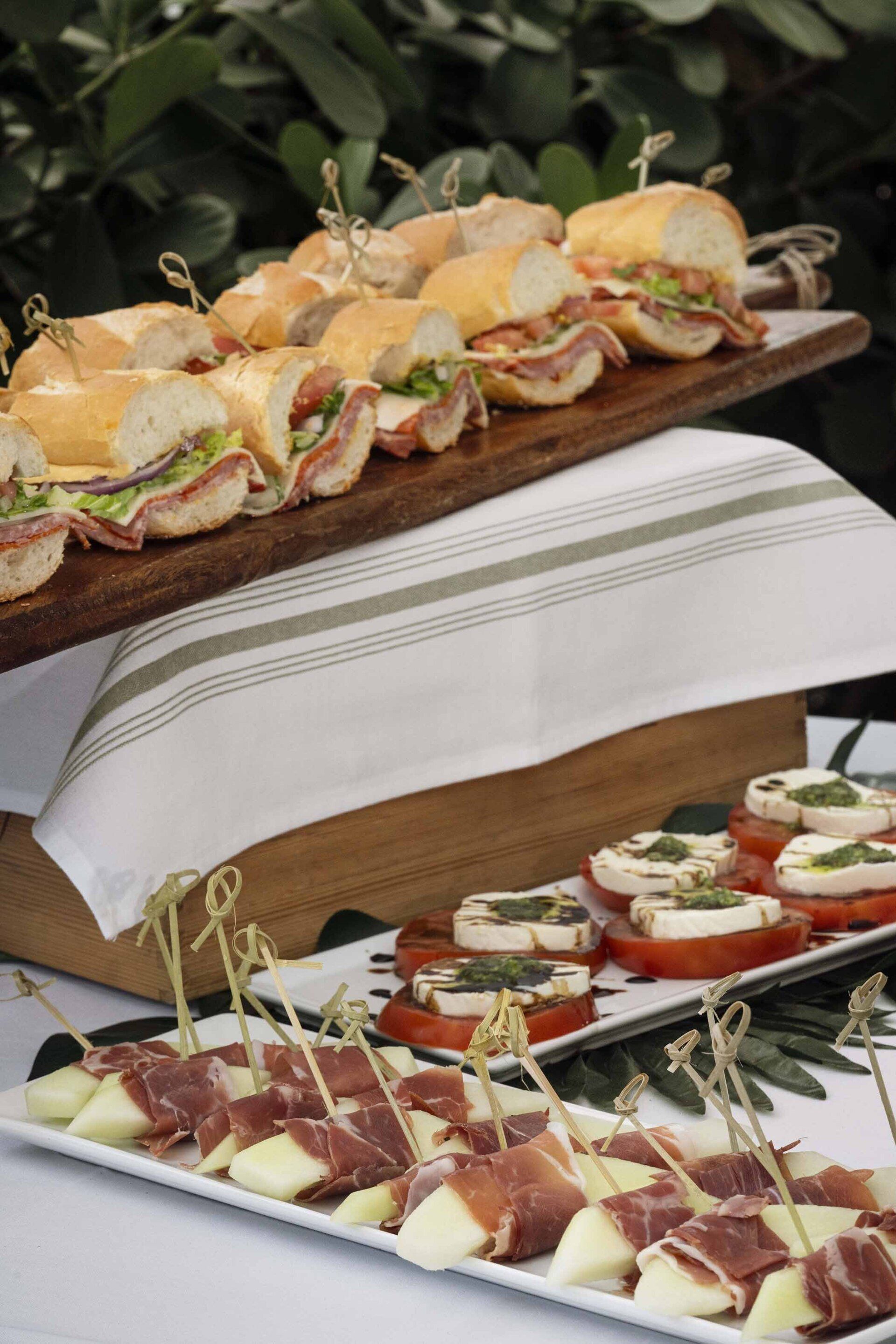 A table topped with plates of food including sandwiches and appetizers.